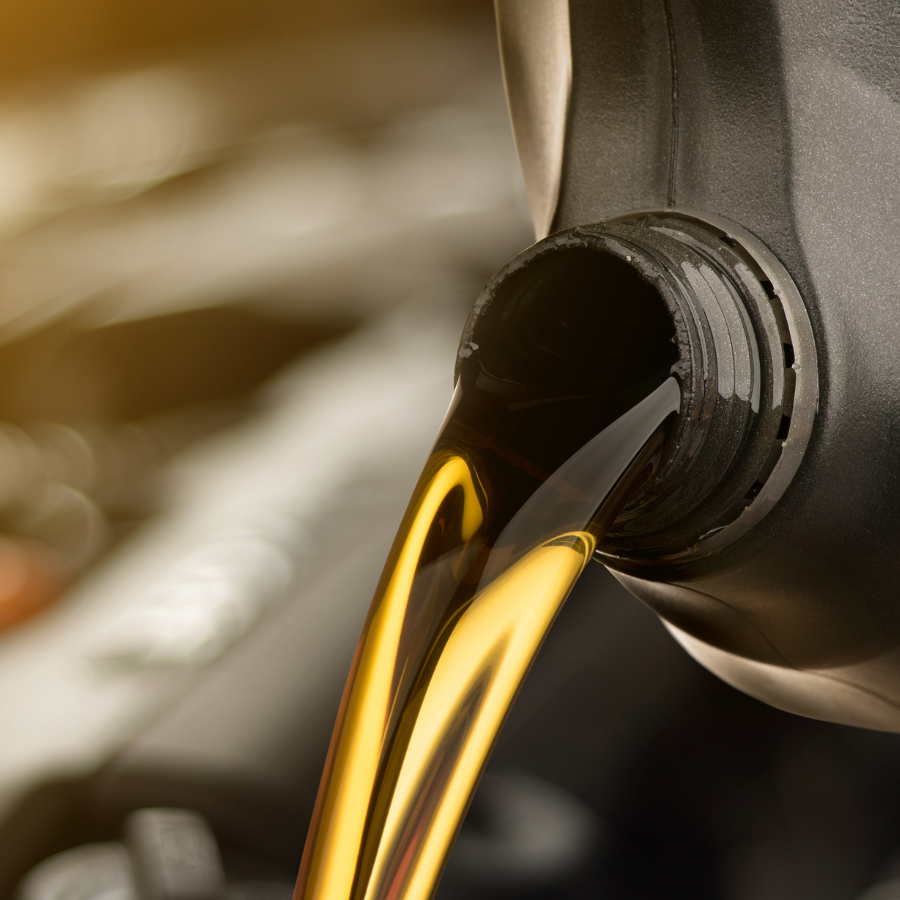 Motor oil poured from a black bottle into a vehicle's oil pan